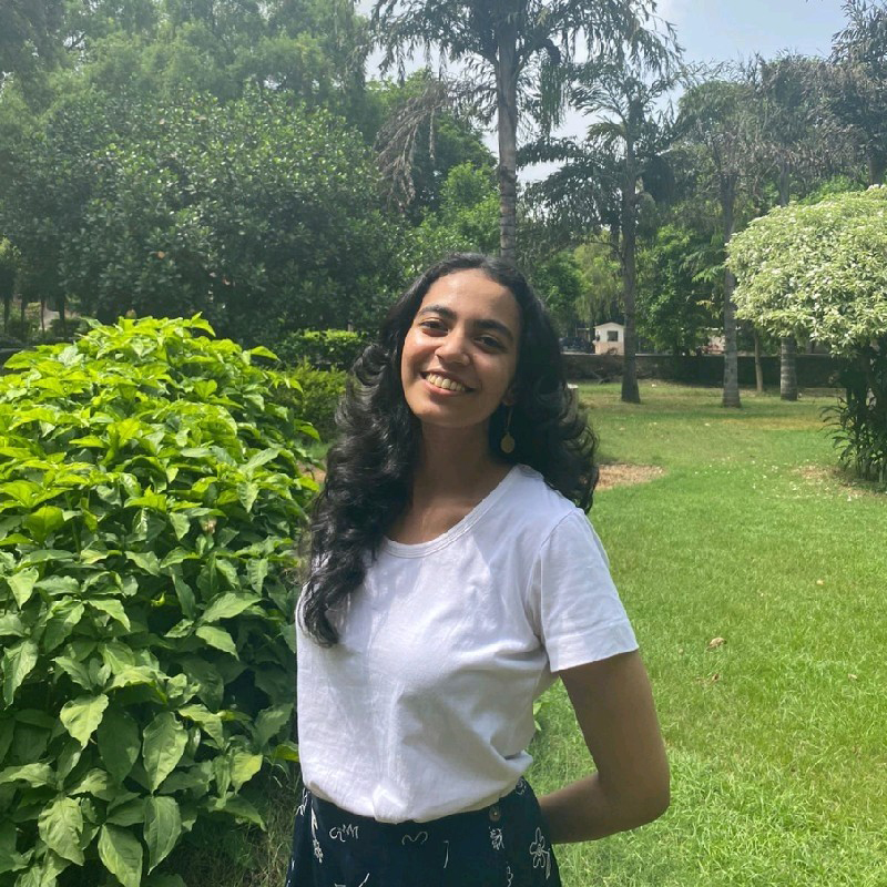 Portrait of Renee standing in a garden surrounded by greenery.