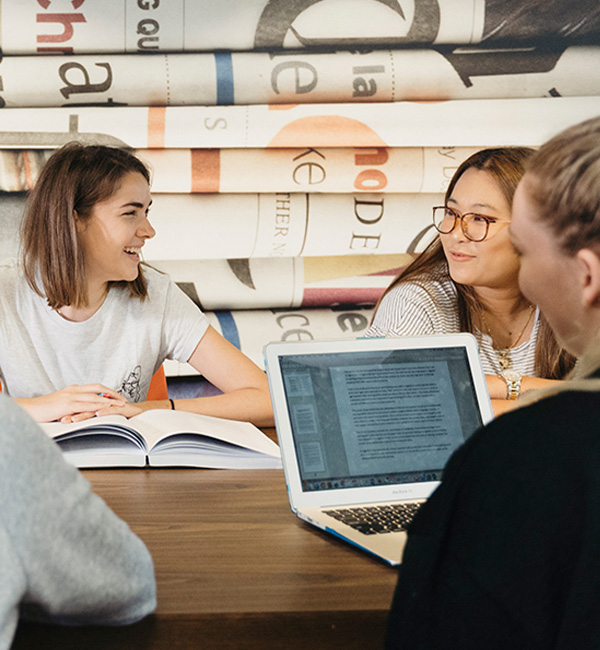 Students gathered around a study table with books and laptops