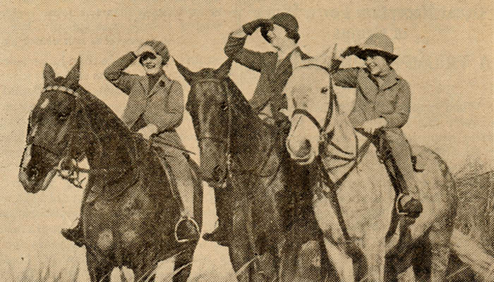 A sepia-toned image from a scanned copy of The Children's Newspaper, showing four people riding horses, each saluting with their right hand, dressed in early 20th-century attire and hats, set against a grassy background.